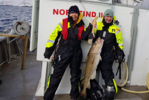 Man and woman holding cod on arctic cod fishing in Lofoten